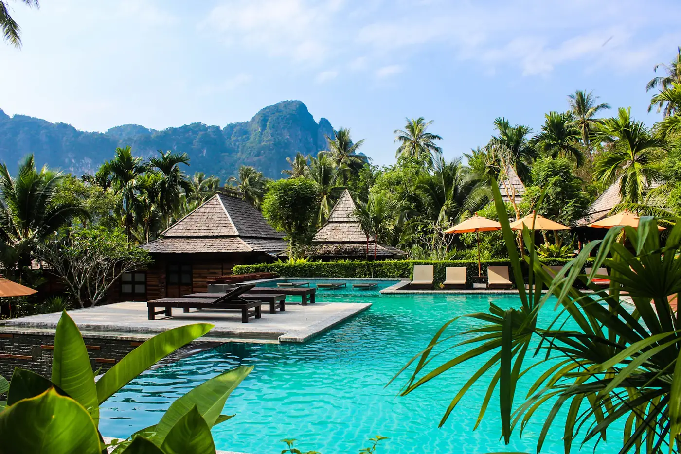 Pool surrounded by jungle and thatched roofs