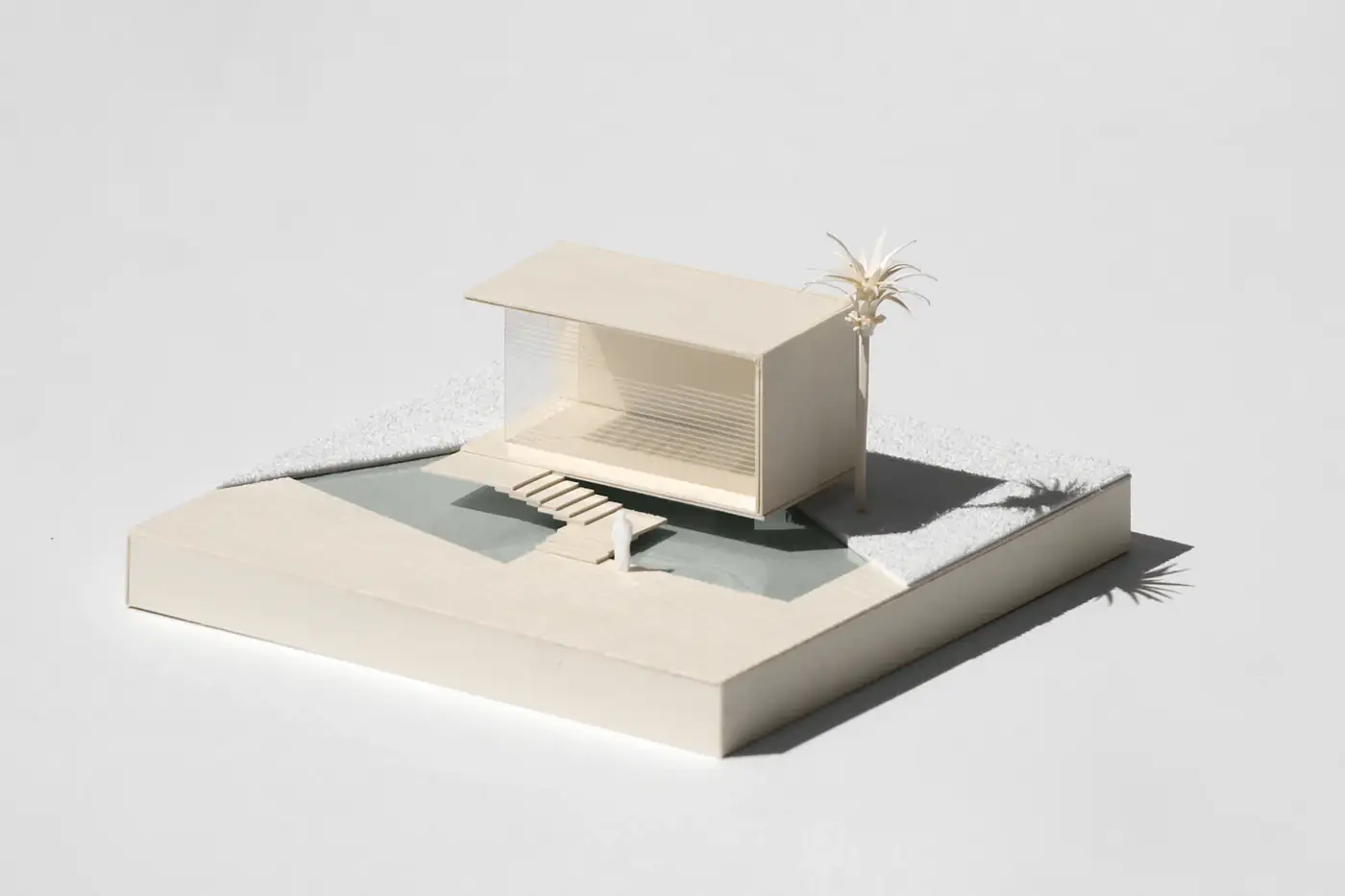White model of a small pavilion beside a palm
