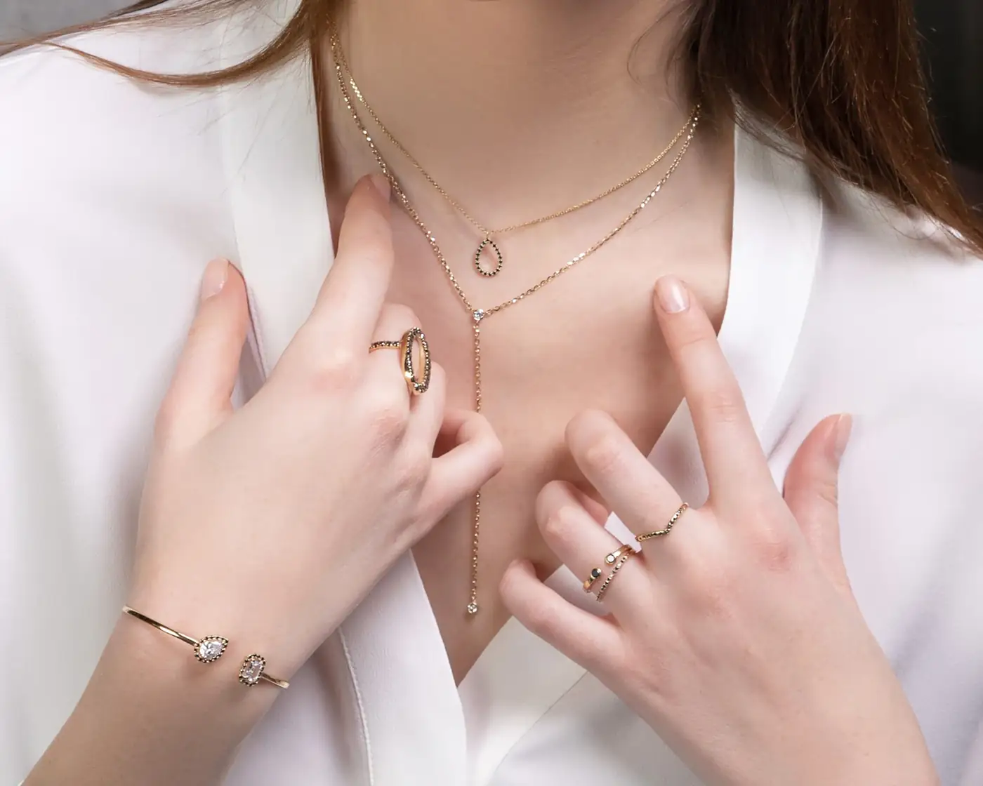 Woman wearing layered gold necklaces and rings