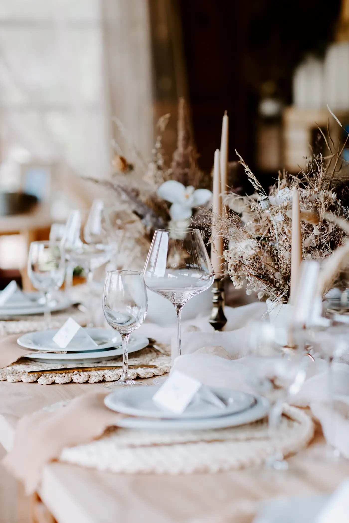 Long table with candles, dried flowers and glassware
