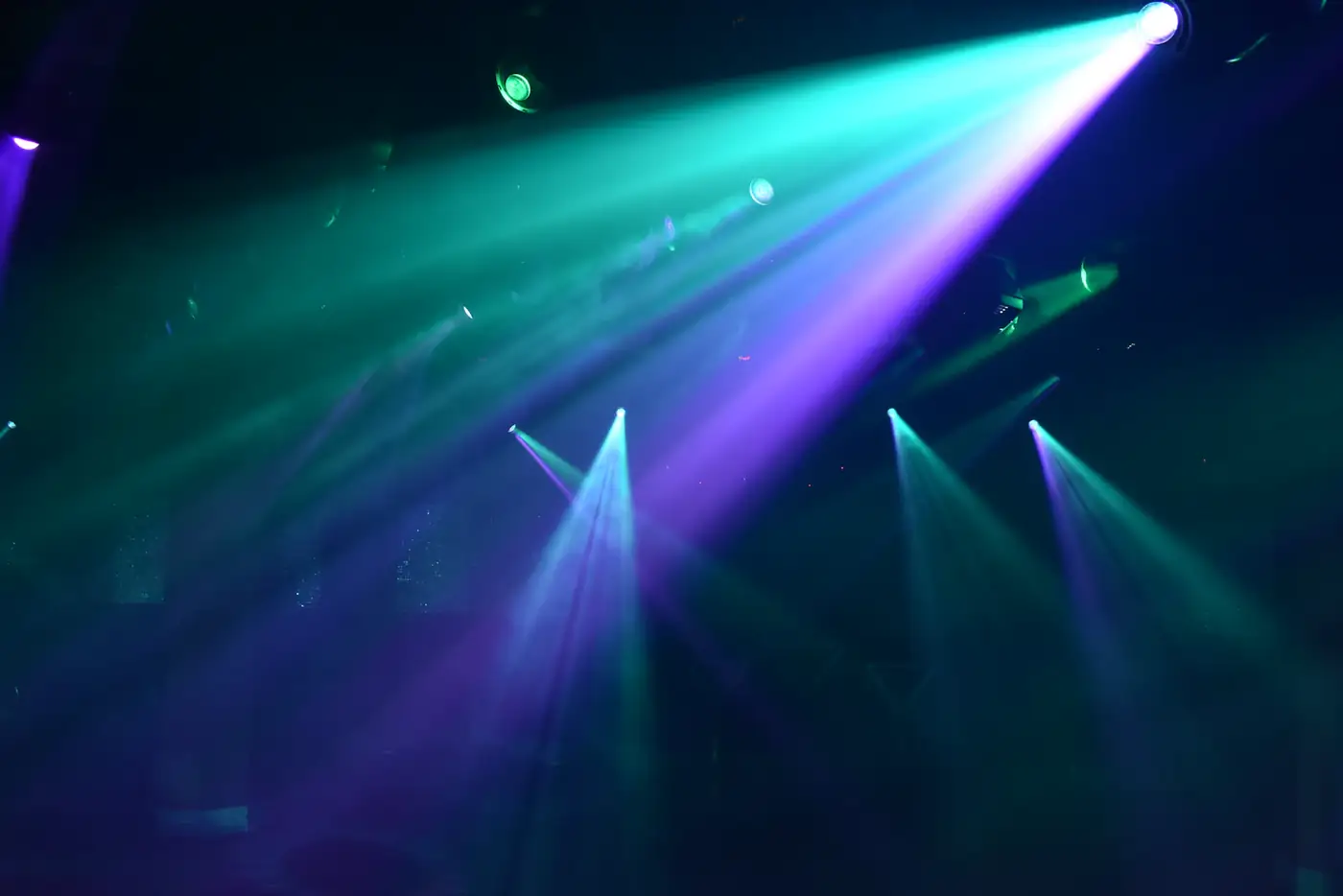 Teal and violet laser beams cutting through haze