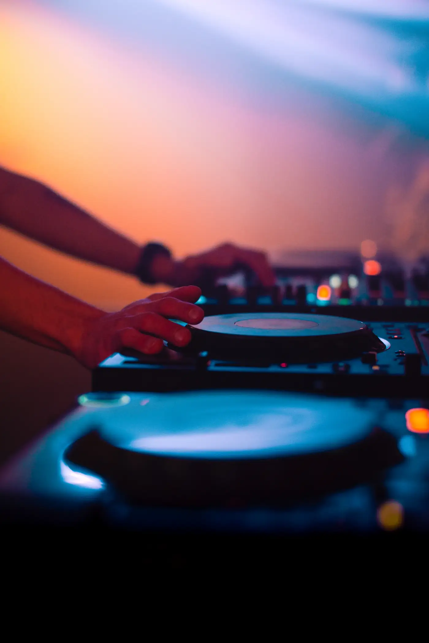 DJ hands on decks at sunset
