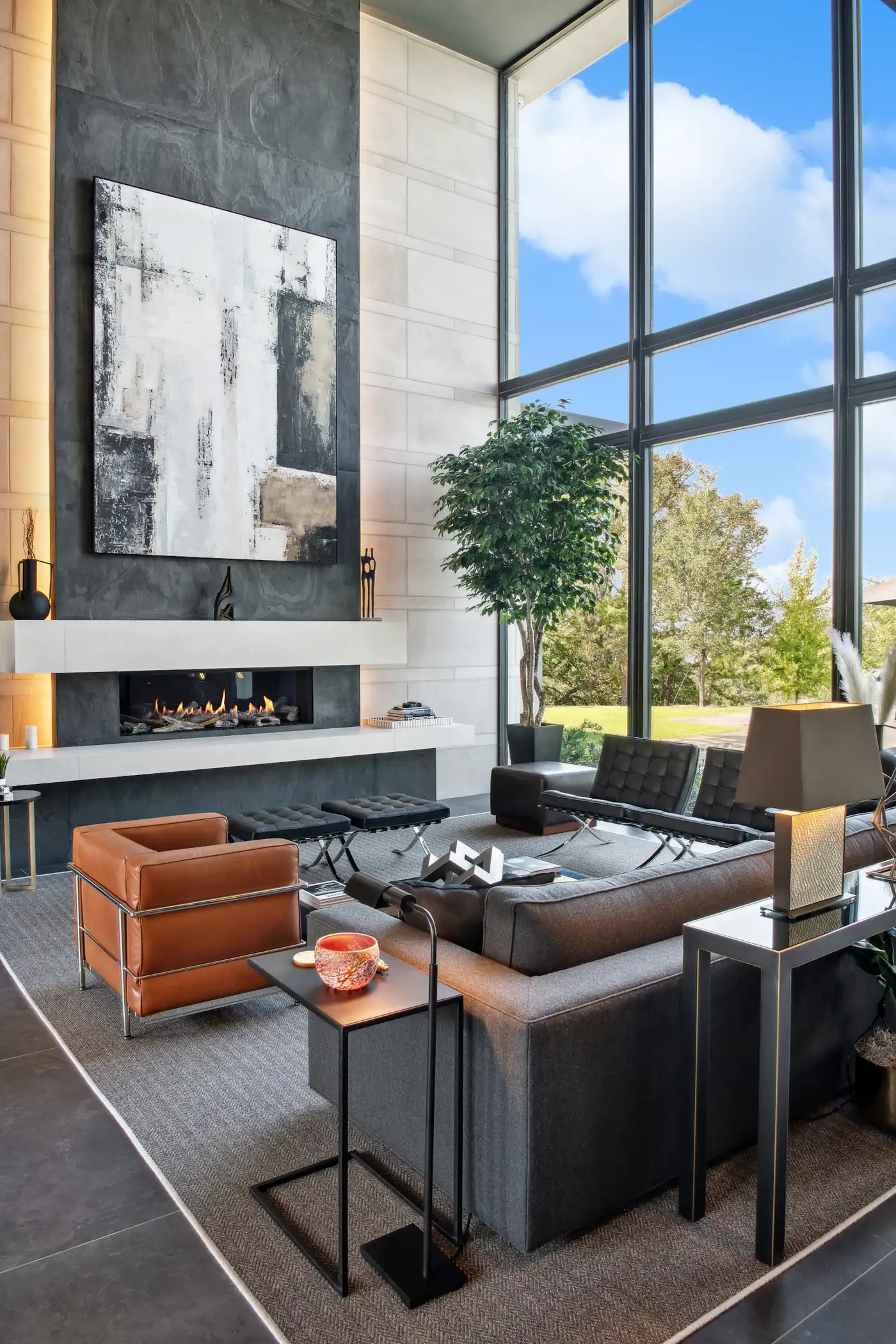 Living room with a fireplace and tall windows to the trees