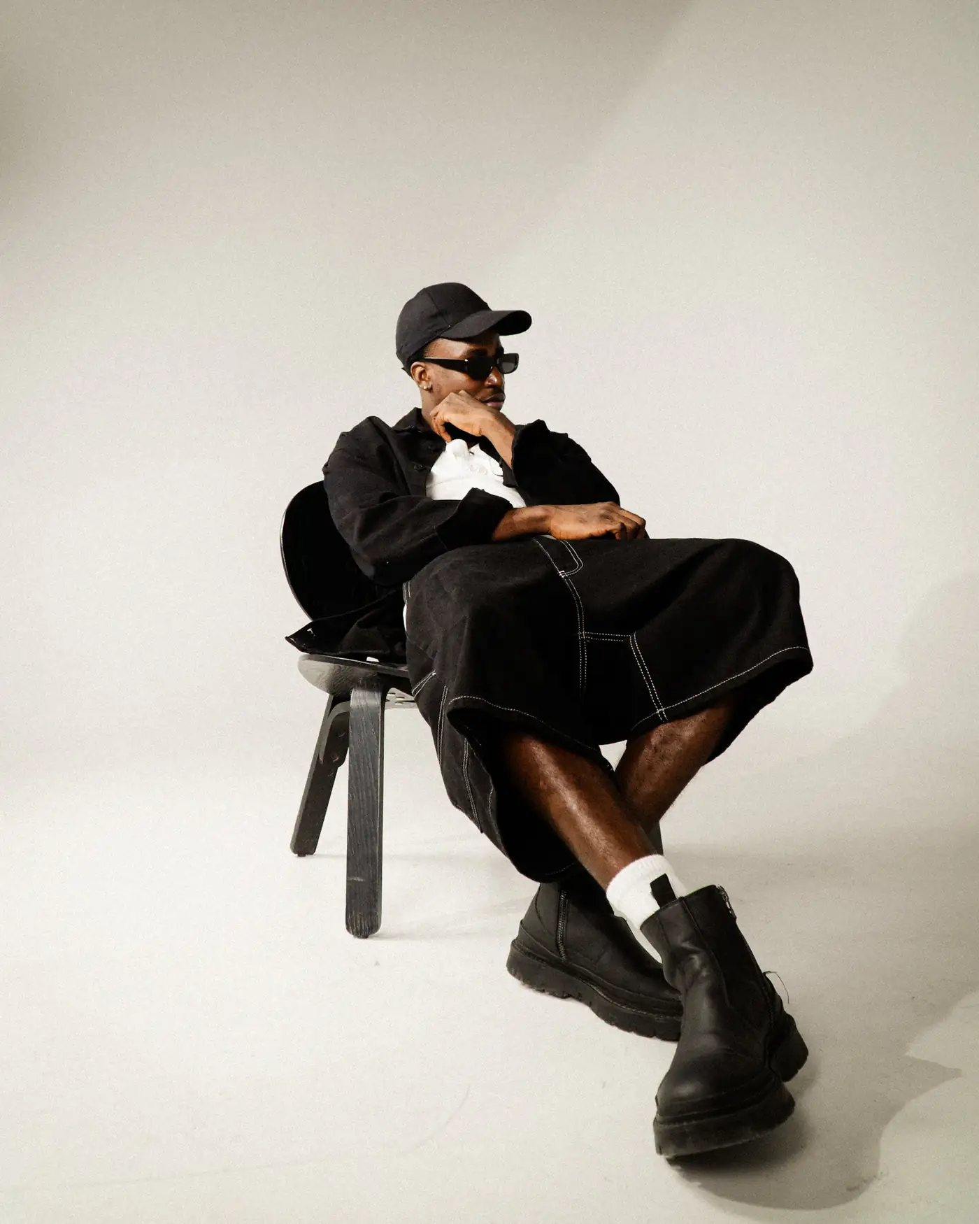 Model seated on a stool in black streetwear