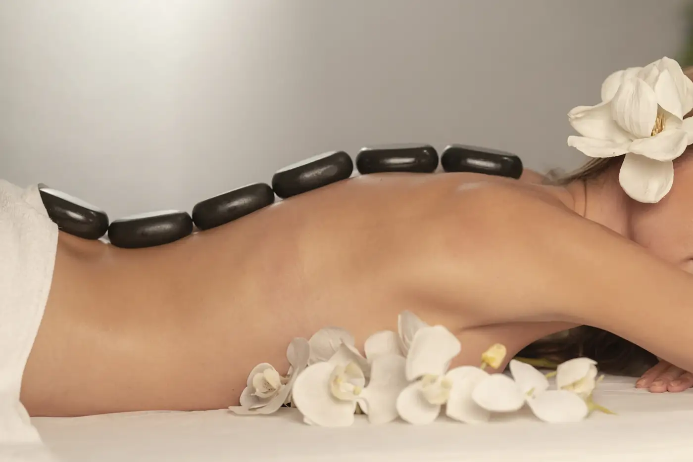 Hot stones along a back with white orchids
