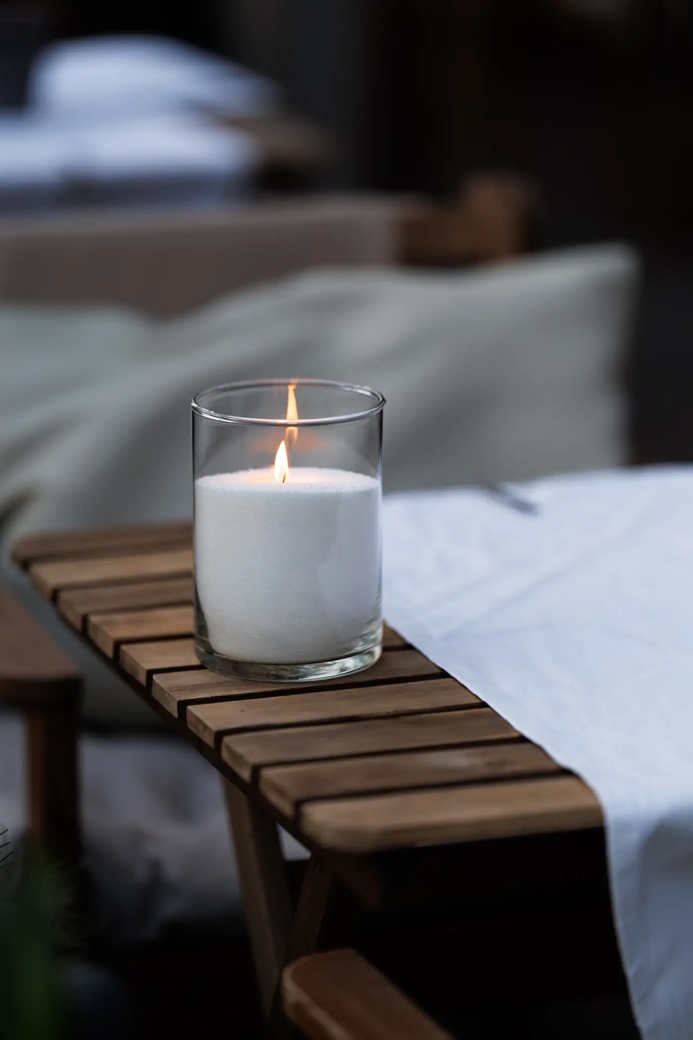 Candle on a wooden stool beside a massage bed