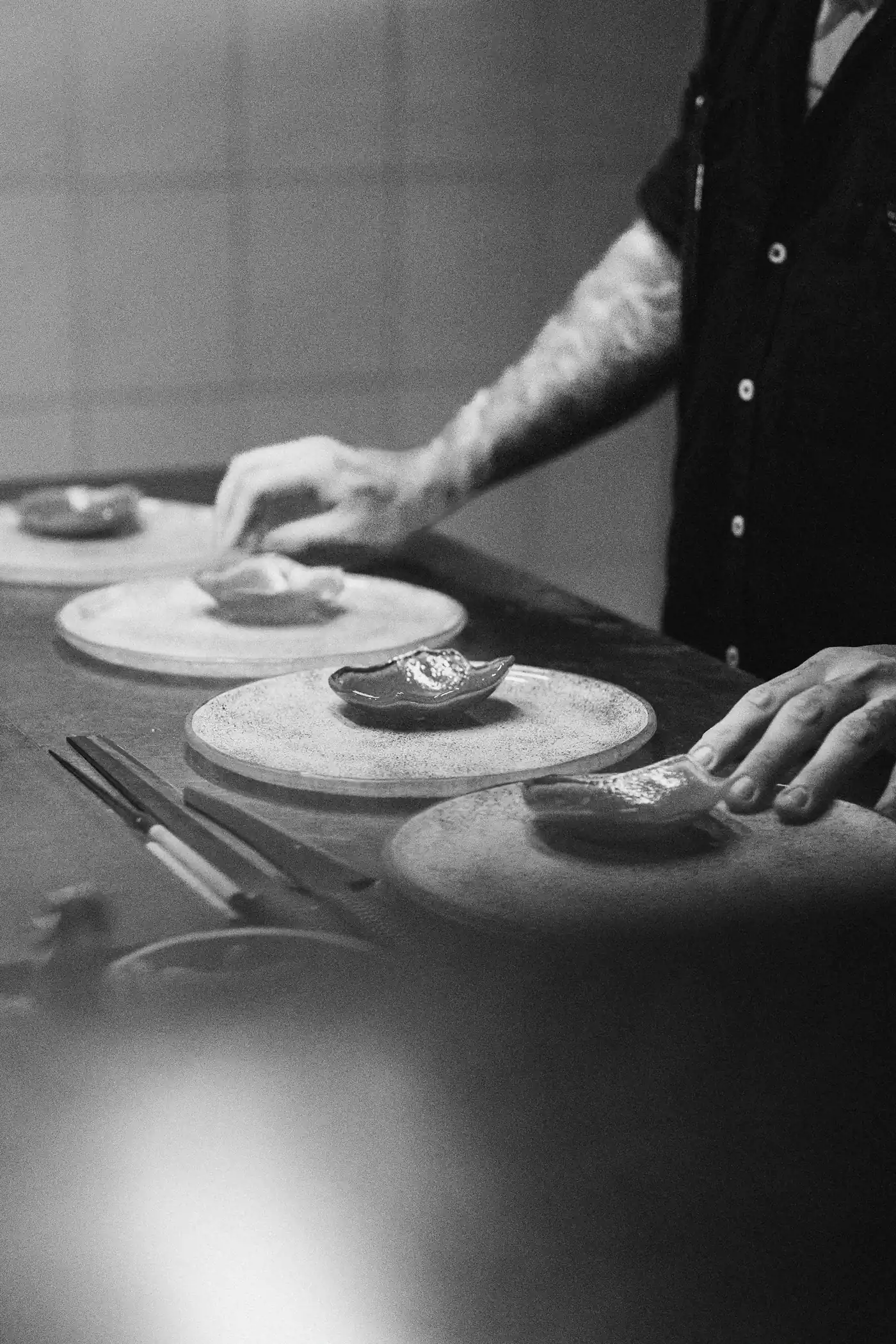 Black and white photo of a chef plating several dishes