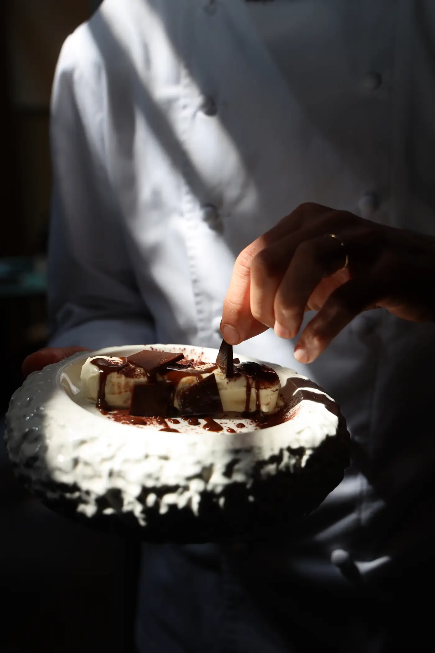 Chef spooning dessert into a textured bowl