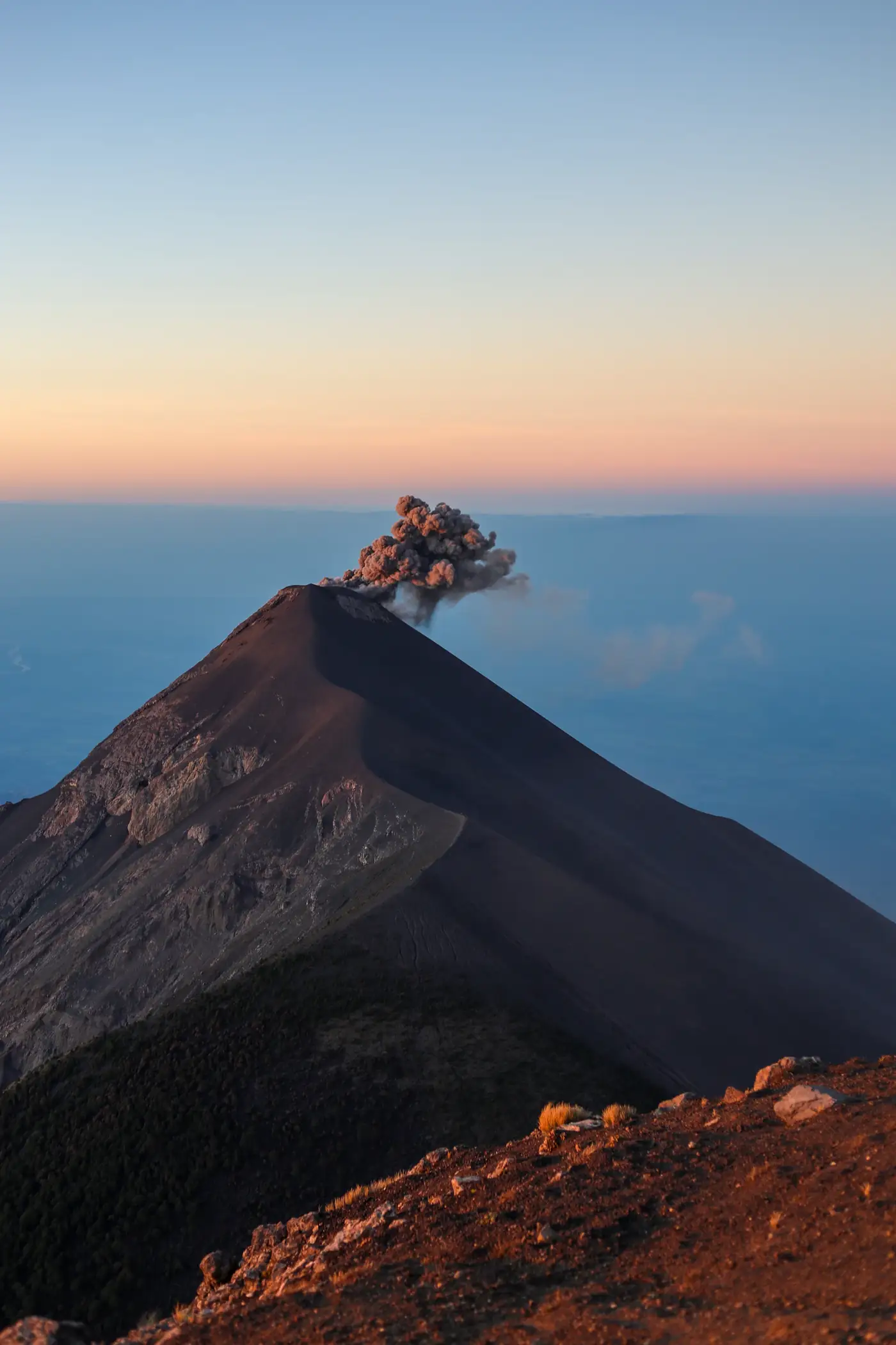 A volcano puffing ash into a sunset sky